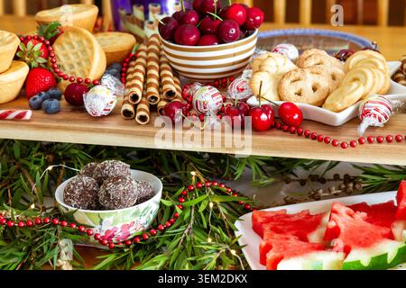 Umfassender mehrstufiger Urlaubs-Desserttisch gefüllt mit Hackkuchen, Torten, Erdbeeren, Shortbread-Keksen, Trüffeln, und Wassermelonenbäume. Stockfoto