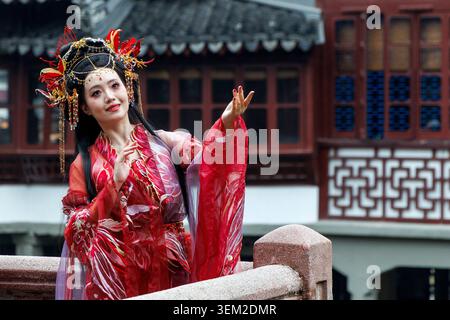 Frau in rotem Hanfu-Kleid und kunstvollem Kopfschmuck posiert im Yu Garden, Shanghai, China Stockfoto