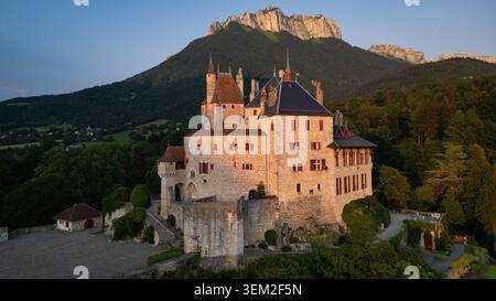Menthon-Saint-Bernard, Frankreich - 09. Juli 2023: Aus der Vogelperspektive des Chateau de Menthon-Saint-Bernard mit seinen Steinmauern und Türmchen bei Sonnenuntergang gegen den b Stockfoto