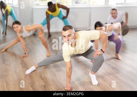Junger Trainer, der das Aufwärmen vor dem Gruppentanztraining leitet Stockfoto