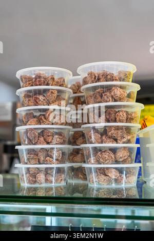 Traditionelle chinesische Huamei getrocknete Pflaumen in Plastikbehältern, die auf einem Glasregal in der Süßwarenbäckerei in Macau gestapelt sind Stockfoto