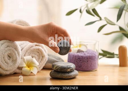 Weibliche Hand, die Spa Stein vom Tisch im Salon nimmt, Nahaufnahme Stockfoto