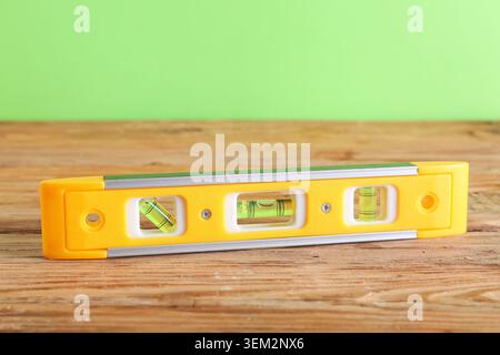 Wasserwaage auf Holztisch vor grünem Hintergrund Stockfoto