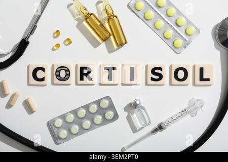 Wort CORTISOL mit Pillen, Ampullen und Stethoskop auf grauem Hintergrund. Medizinisches Konzept Stockfoto