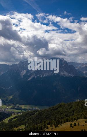 Blick auf die majestätischen Dolomiten mit zerklüfteten Gipfeln, die teilweise von dramatischen Wolken über bewaldeten Hängen und einem Tal in Rocca Piet umgeben sind Stockfoto