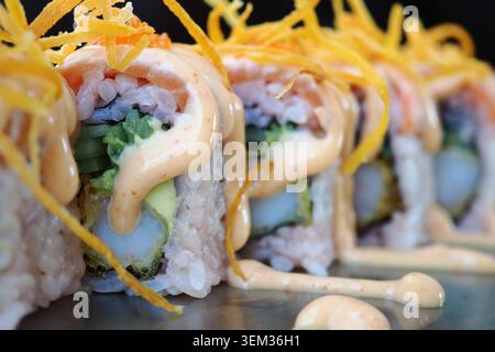 Sushi-Brötchen mit Sauce und Belägen auf einem Teller Stockfoto
