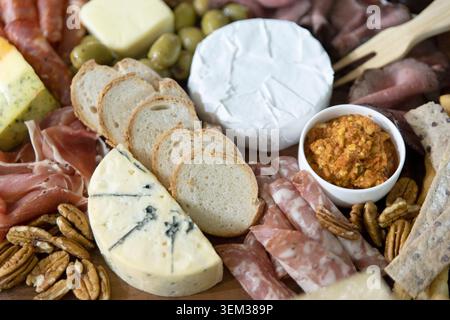 Aus nächster Nähe auf eine Gourmet-Wurstplatte mit Brie-Käse, geschnittenem Baguette-Brot, Salami und Pekannüssen. Stockfoto