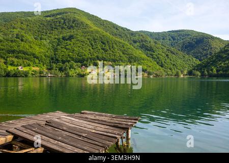 Alte hölzerne Pier am Pliva See mit grünen Bergen in Jajce, Bosnien und Herzegowina Stockfoto