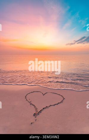 Süßes Herz, das im Sand am tropischen Strand bei romantischem Sonnenuntergang und ruhigem Meer gezeichnet wurde. Liebe Valentinstag Flitterwochen. Sommerreise Urlaub Ferienparadies Insel Stockfoto
