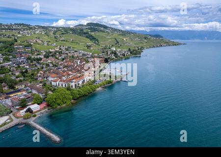 Aus der Vogelperspektive auf die historische Stadt Lutry am Ufer des Genfer Sees mit üppigen Weinbergen und sanften Hügeln unter bewölktem Himmel über Lutry, Waadt und Swit Stockfoto