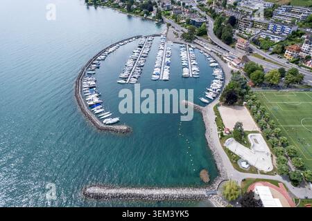 Aus der Vogelperspektive auf den Hafen und den Yachthafen von Lutry mit verankerten Booten und einem geschwungenen Wellenbrecher am Ufer des Genfer Sees in Lutry, Waadt, Schweiz. Stockfoto