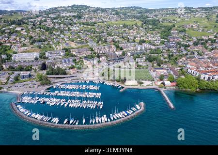 Blick aus der Vogelperspektive auf den kreisförmigen Hafen mit Segelbooten und die Wohnstadt Lutry am Ufer des Genfer Sees, Lutry, Waadt, Schweiz. Stockfoto
