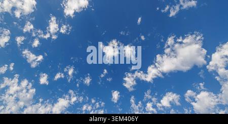 Tiefer blauer offener Himmel, eingerahmt von weichen weißen Wolken mit breitem Kopierraum. Sonniges Sommer-Wolkenhimmel-Wetter-Hintergrund. Friedlicher Himmels-Natur-Hintergrund Stockfoto