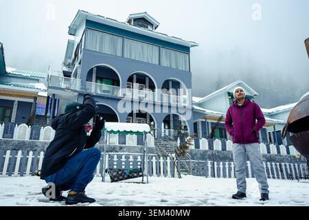 Zwei Touristen posieren und fotografieren vor einem malerischen Berghotel in Kaschmir, Indien. Stockfoto