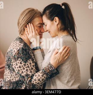 Die erwachsene Tochter umarmt liebevoll ihre ältere Mutter Stockfoto