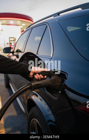 Nahaufnahme des Handsteckens eines Ladegeräts an ein Elektroauto Stockfoto