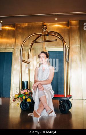 Frau, die auf einem Pagenwagen sitzt, mit elegantem Kleid Stockfoto