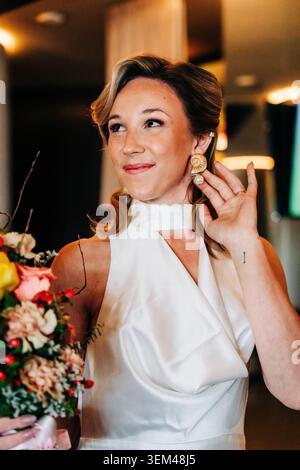 Die Braut trägt ein elegantes Hochzeitskleid und Muschelohrringe Stockfoto