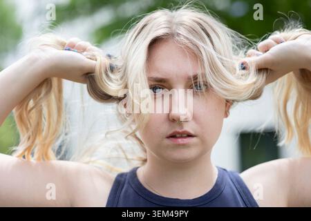 Eine junge Frau, die im Garten steht und Haare hält Stockfoto