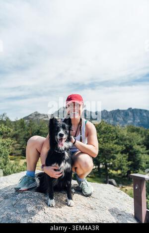Glückliche Frau und Hund posieren auf einer Bergwanderung Stockfoto