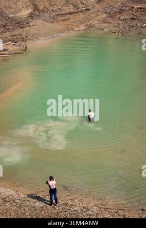 Frau fotografiert Freunde, die im grünen Wasser waten Stockfoto