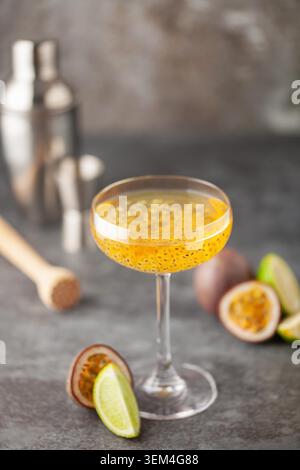 Martini-Cocktail mit Passionsfrucht. Saures alkoholisches Getränk mit frischem Passionsfrucht und Limette, mit Barwerkzeugen. Stockfoto
