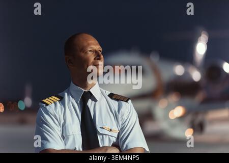 Selbstbewusster, männlicher Flugkapitän mit vier goldenen Streifen und Flügeln in formellem hellblauem Uniformhemd und schwarzer Krawatte, die auf der Werbung stehen Stockfoto