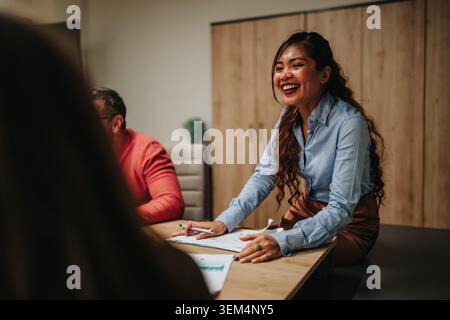 Ein lächelnder Geschäftsteams leitet ein Meeting und präsentiert Kollegen Dokumente an einem Konferenztisch Stockfoto