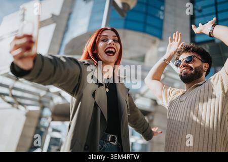 Glückliche Freunde, die gemeinsam ein Selfie auf einem städtischen platz vor einem modernen Bürogebäude machen Stockfoto