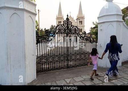 Mutter und Tochter gehen auf einer Straße vorbei an der örtlichen Kirche in kochi in kerala in indien Stockfoto
