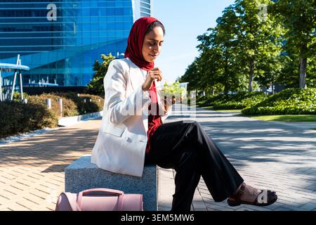 arabische Geschäftsfrau aus dem Nahen Osten im Hijab, die in der Stadt schlendert - muslimische Geschäftsfrau, die eine gesunde Mittagspause in einem Stadtpark genießt Stockfoto