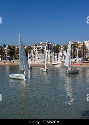 Sitges, Spanien - 8. April 2025: Ein malerischer Blick auf mehrere kleine weiße Schlauchboote, die auf dem ruhigen blauen Mittelmeer in der Nähe des sandigen beac schwimmen Stockfoto