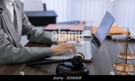 Professioneller Rechtsanwalt mit Laptop-Computer, Rechtsrecherche am Büro der Anwaltskanzlei mit Hamelwaage Stockfoto