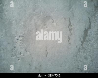 Ein hochwinkliger Drohnenschuss, der die abstrakte, strukturierte Oberfläche eines gefrorenen Eisfeldes mit leichtem Schnee erfasst. Dieser kalte, minimalistische Naturhintergrund Stockfoto