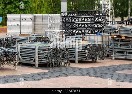 Gerüstrohre aus Metall und Bühnenbalken, gestapelt für Konzerte im Freien in einem Stadtpark. Stockfoto