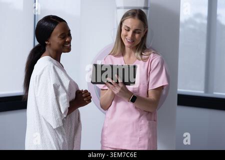 Afroamerikanerin und Technikerin bei Scrubs, die Scans mit Tablette nach Gantry überprüfen. Bildgebung, Radiologie, Diagnostik, Klinik, Technologis Stockfoto