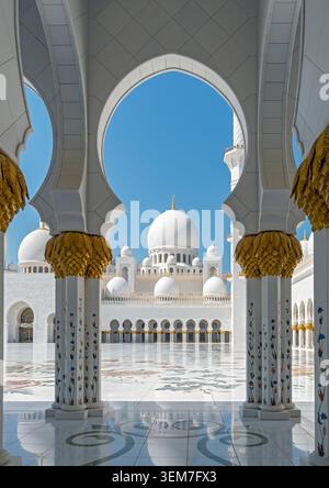 Ein Blick durch einen eleganten Marmorbogen, der in den Haupthof und in Richtung der zentralen Kuppeln führt, Scheich Zayed-Moschee, Abu Dhabi, VAE Stockfoto