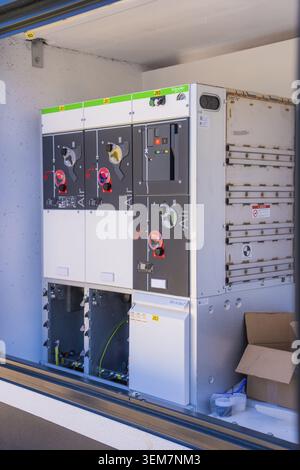 Nahaufnahme eines geöffneten Schaltkastens mit detaillierten Verkabelungs- und Schaltinstrumenten, Transformator und Wechselrichter für ein 10-MW-Agrar-PV-System Stockfoto