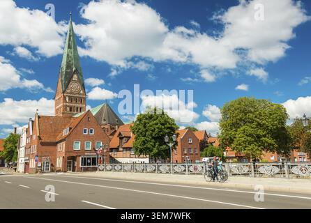 Lüneburg - Juli 2018, Niedersachsen, Deutschland: Menschen zu Fuß über die Brücke. Dom und Alte historische Häuser mit blauem Himmel und Wolken auf der Rückseite Stockfoto