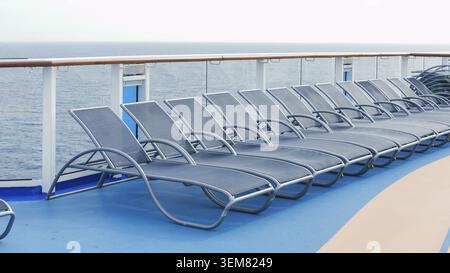 Ein ruhiger Blick auf blaue Liegestühle, die perfekt in ordentlichen Reihen auf einem luxuriösen Kreuzfahrtdeck angeordnet sind Stockfoto