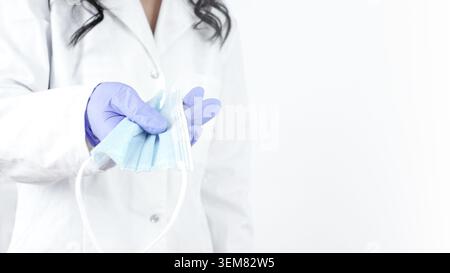 Nahaufnahme der Ärztehand, die eine medizinische Gesichtsmaske hält, auf weißem Hintergrund Stockfoto