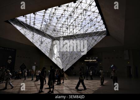 Weite Sicht auf Besucher, die unter der inversen Glaspyramide im Louvre in Paris Frankreich spazieren gehen und Fotos machen Stockfoto