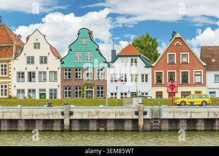 Kleine schöne europäischen Stadt. Fassaden der alten historischen Häusern. Gelbe Auto auf dem Ufer des Flusses geparkt. Glückstadt, Deutschland Stockfoto