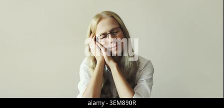 Müde überarbeitete schlafende junge Angestellte, während sie morgens am Schreibtisch im Büro saß Stockfoto