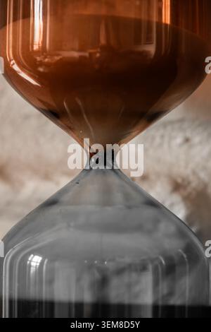Makrofoto einer dekorativen Sanduhr aus Glas mit feinem Sand, der durch ein schmales Zentrum fließt. Symbolische Darstellung von Zeit, Countdown, Geduld, Stockfoto