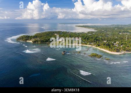 Blick aus der Vogelperspektive auf die Cloud 9 Surfzone mit der berühmten Holzpromenade, Surfern im türkisfarbenen Wasser und üppigen Palmen am Strand in General Luna, Stockfoto