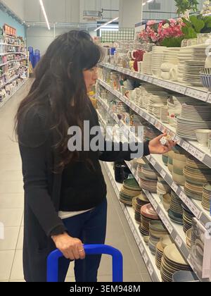 Cremona, Italien - 9. Mai 2026 Frau mit Schwerpunkt auf Geschirr in einem Gang, sorgfältig ausgewählte Küchenartikel aus zahlreichen Optionen, die moderne s repräsentieren Stockfoto