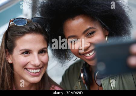 Selfie, Lächeln und Freundinnen in der Stadt, um sich im Urlaub, Kurzurlaub oder Wochenendausflug mit Erinnerungen zu verbinden. Glücklich, Verbundenheit und Frauen mit Fotografie Stockfoto