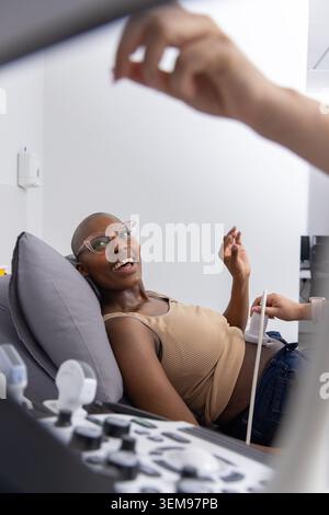 Afroamerikanischer Patient, der auf dem Untersuchungsstuhl liegt, während der Arzt mit Ultraschallsonde in der Klinik arbeitet. Sonographie, Monitor, Schallkopf, Krankenhaus, Gesundheit Stockfoto