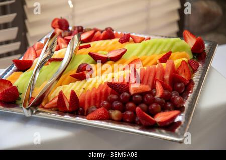 Ein lebhaftes Serviertablett mit fein angeordneten Melonen, Erdbeeren, Trauben und anderem frischen Obst in eleganter Buffetform Stockfoto
